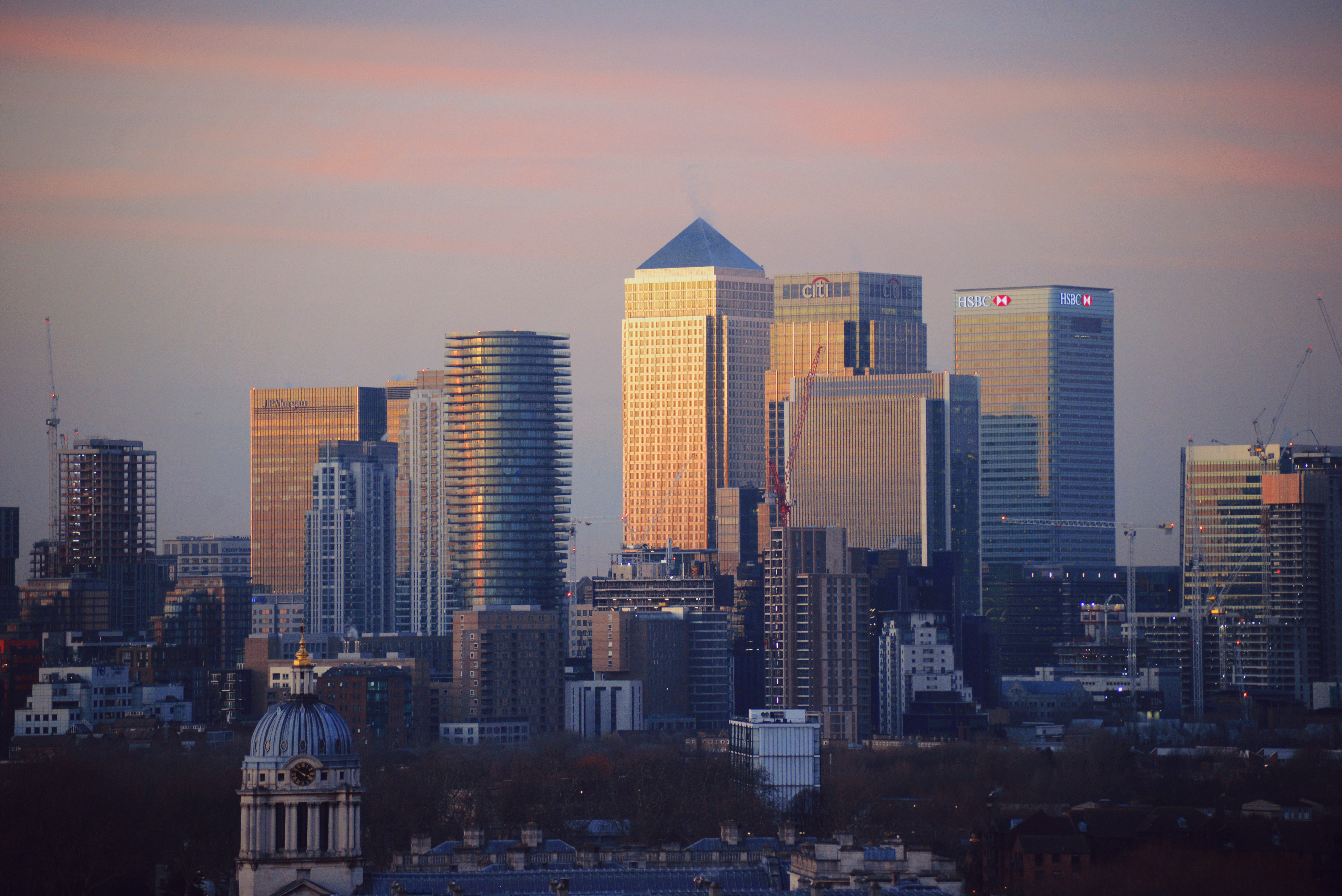 Canary Wharf financial district skyline at sunset, with the towers of major banks lit gold